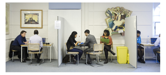 Interviews are set up in three cubicles, each with a student and examiners.

