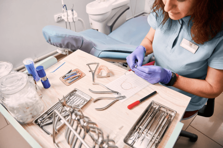 A female orthodontist is working in a dental office, examining a patient's teeth.