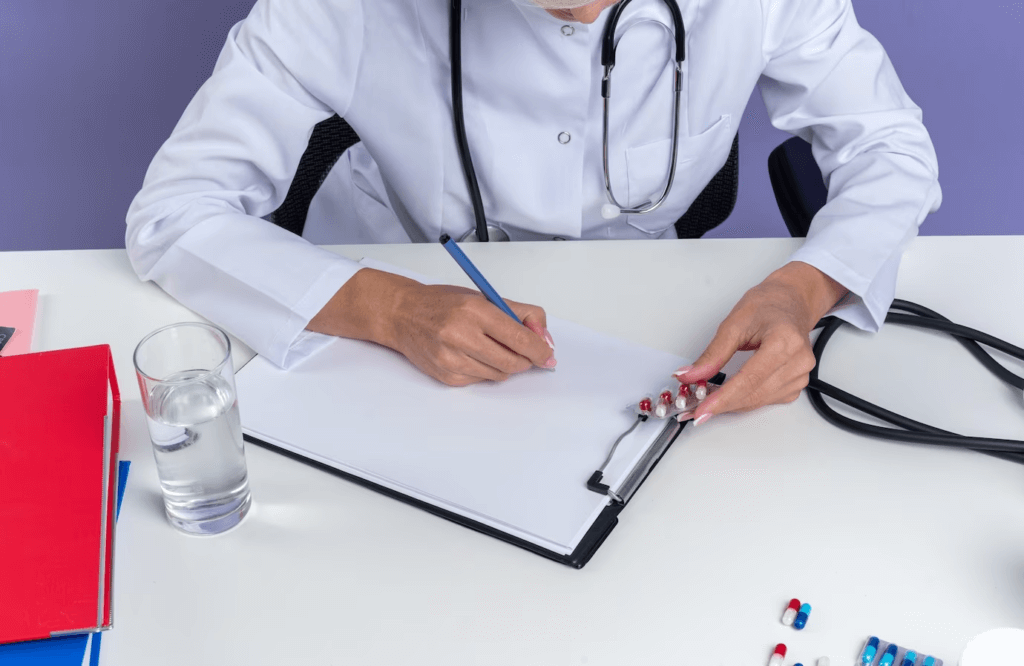 A female doctor in a medical robe, sitting at a desk with a clipboard and pen.