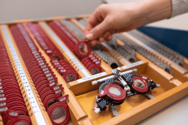 Optometrist selecting lenses during a patient examination.