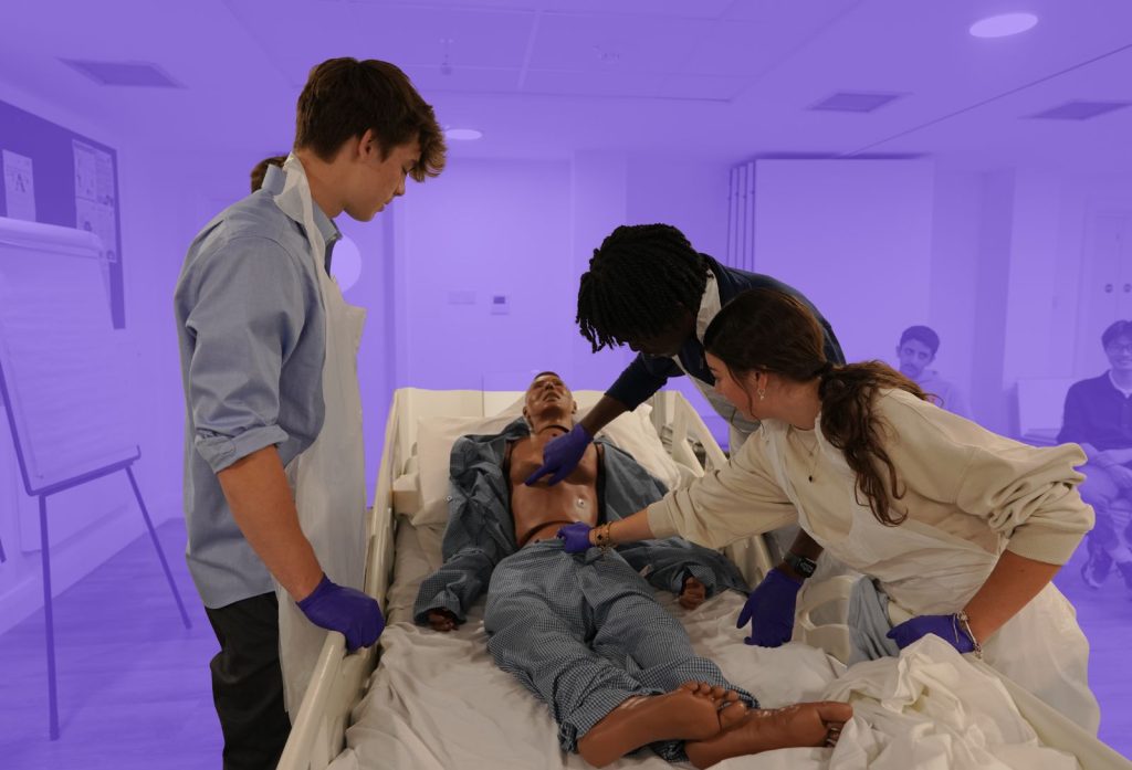 Three students in a simulated emergency scenario visiting a London hospice.